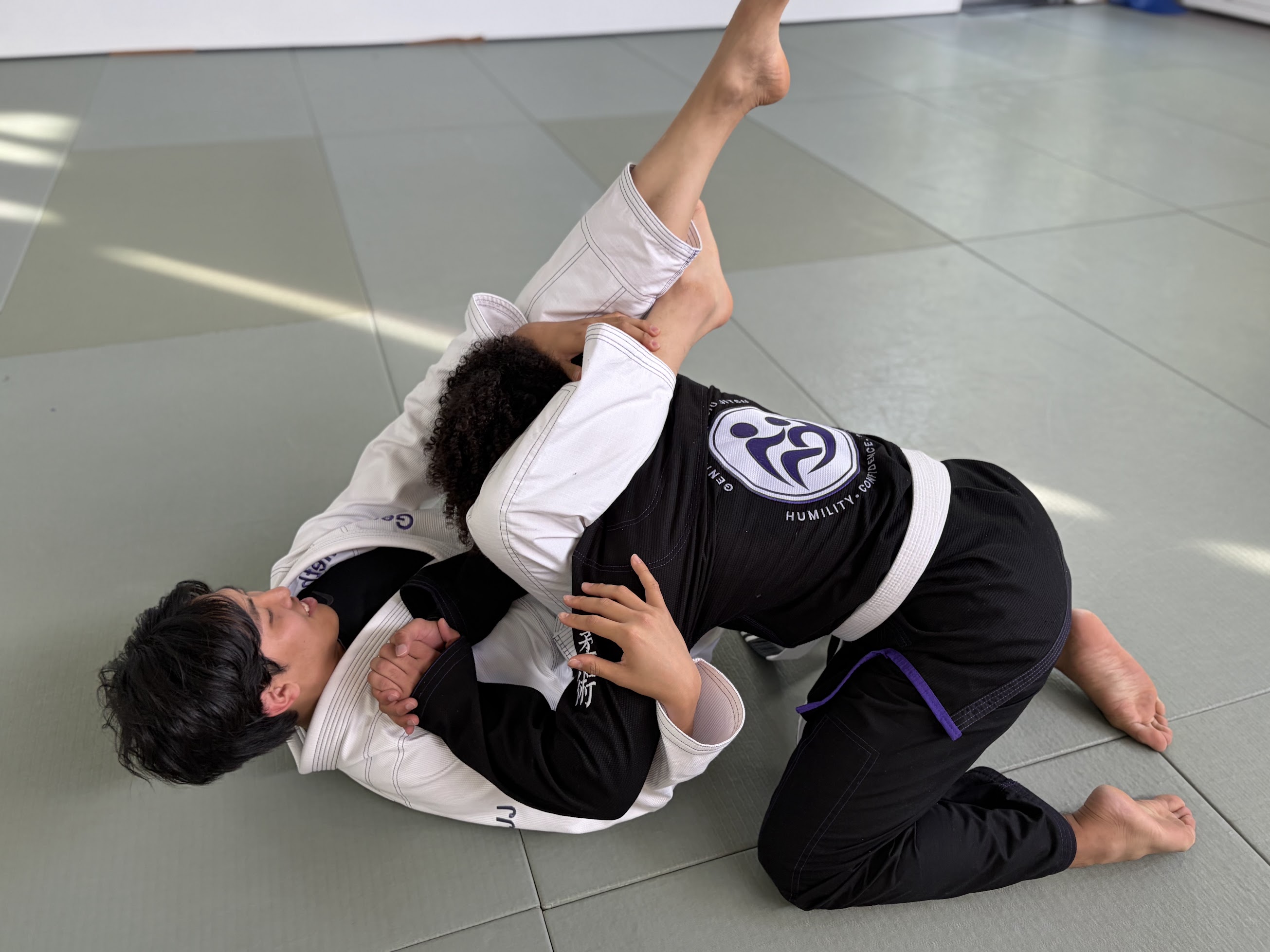 Two students practicing a ground position in class